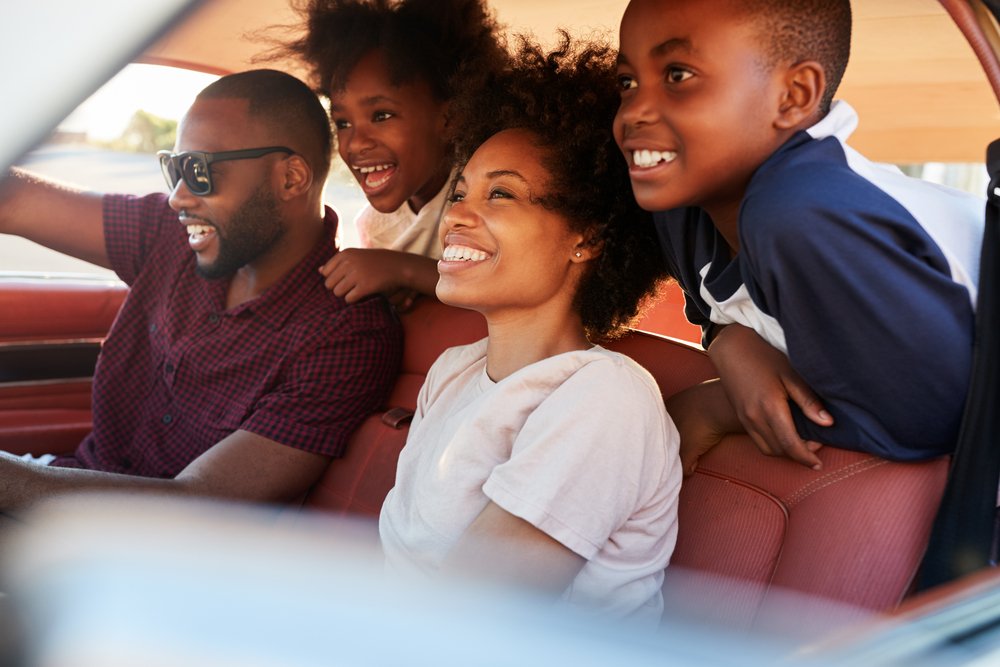 A family gathers toward the front of a car during a drive