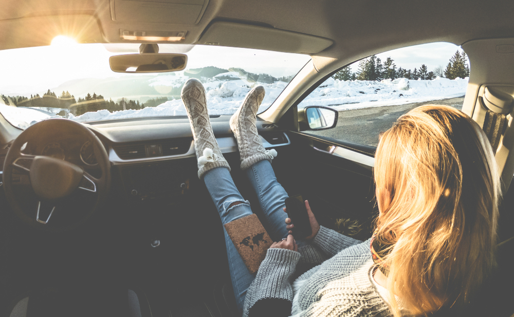 A woman places her feet on the dash 