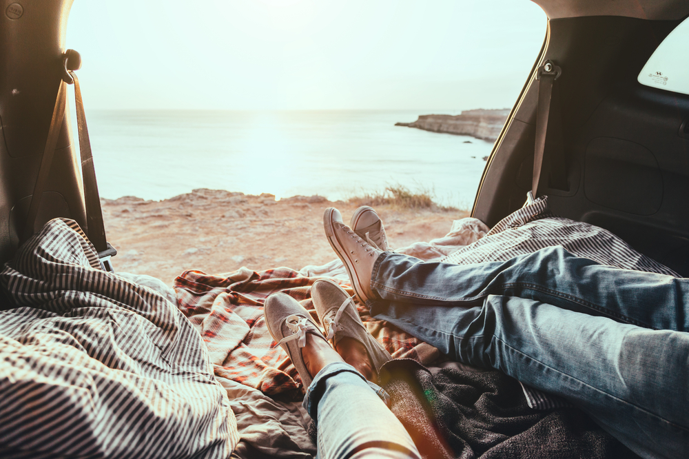 A couple lays and relaxes in the back of a car