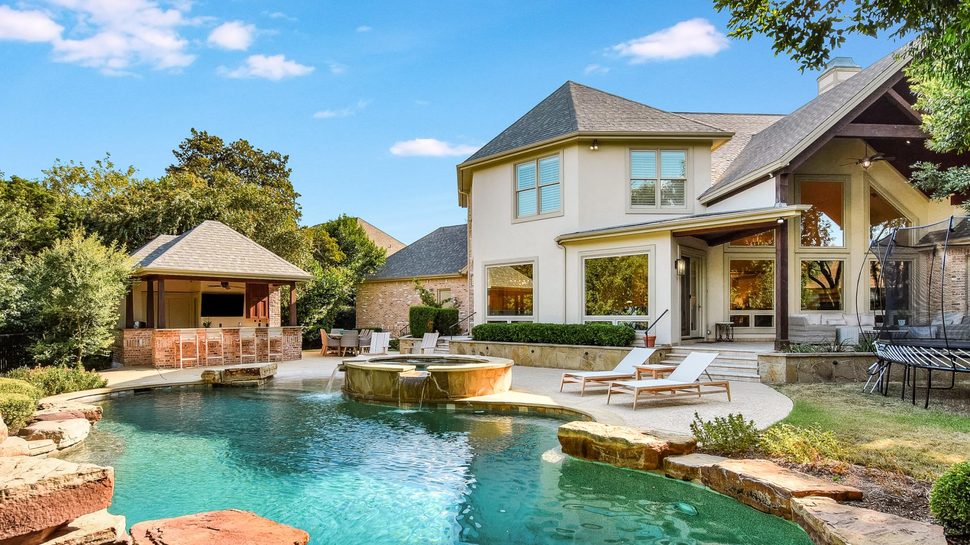 Photo of the exterior of Blue Sky Estate Airbnb including a swimming pool, outdoor kitchen, and lounge area. This is one of the best vacation rentals in Texas. 
