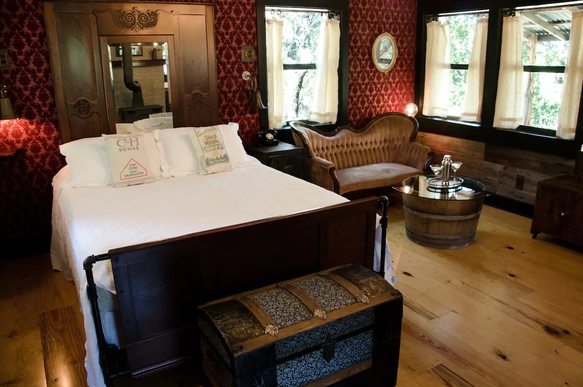 Photo of the romantic, velvet wallpapered bedroom and seating area at The Moonshiner VRBO in Texas. 