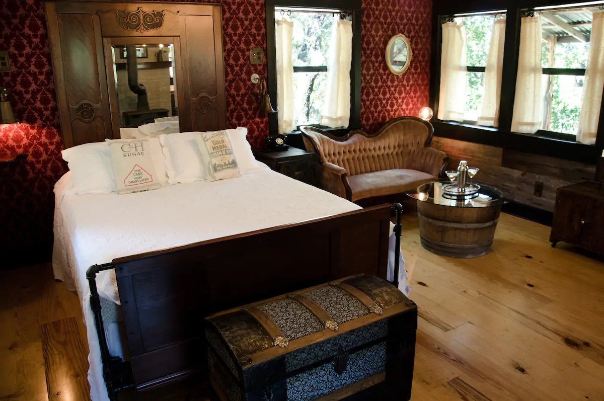 Photo of the romantic, velvet wallpapered bedroom and seating area at The Moonshiner VRBO in Texas.