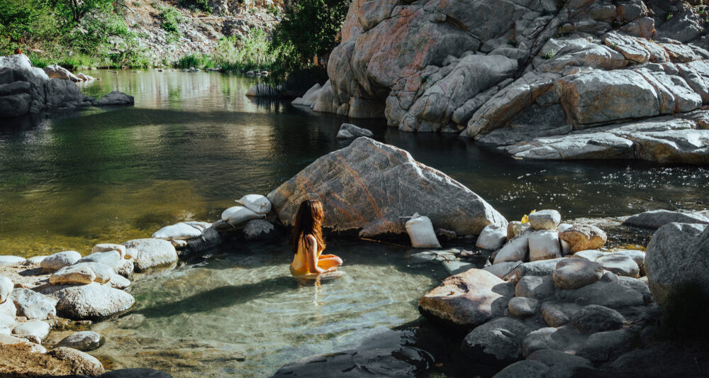 woman sitting in one of the best hot springs in california