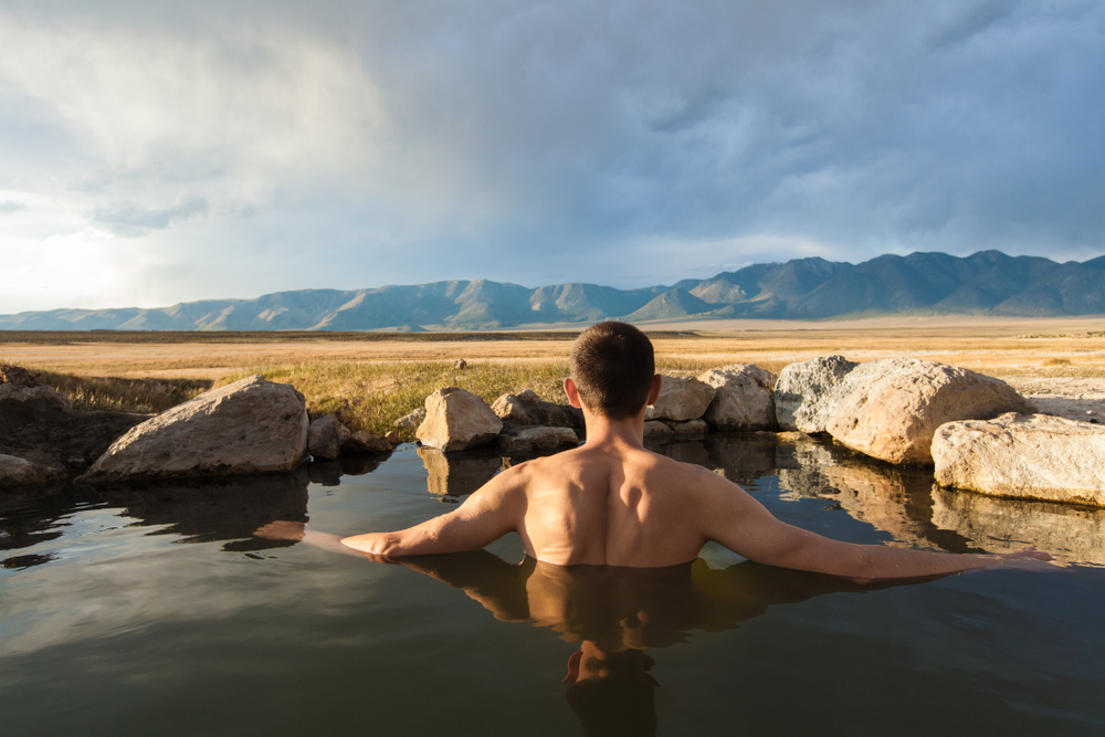 Man relaxing in Wild Willy's Hot Springs, looking out at the view