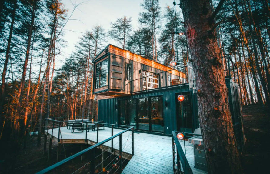 cabin made of three shipping containers stacked on each other in woods in winter