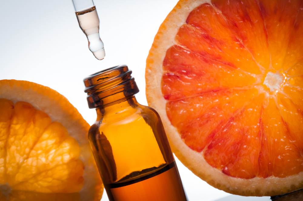 a picture of a oil bottle with oranges around it. 