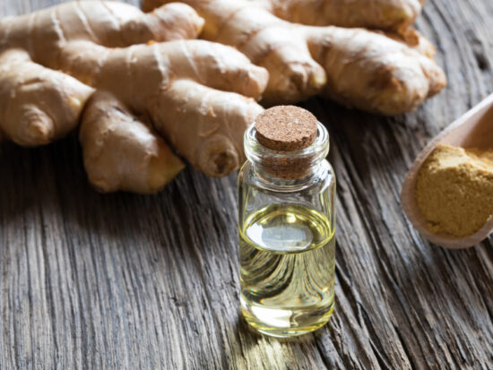 Ginger oil on a table with some raw ginger