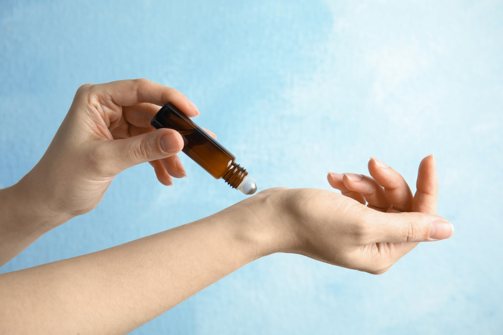 Women using an oil and rubbing it on her wrist. 