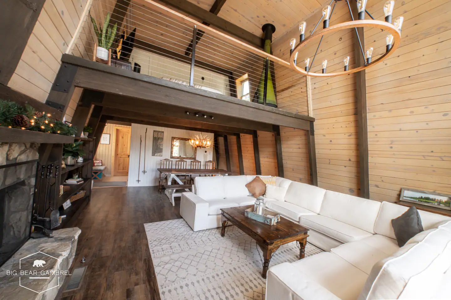 Gorgeous living room in Big Bear cabin, with white couches, fire place, and bulb chandelier. One of the best California Airbnbs.
