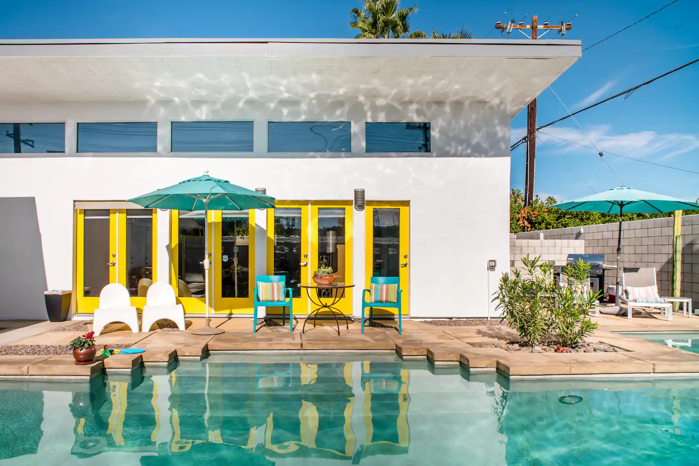 Bright, bold, colorful Airbnb front, with yellow doors and a pool
