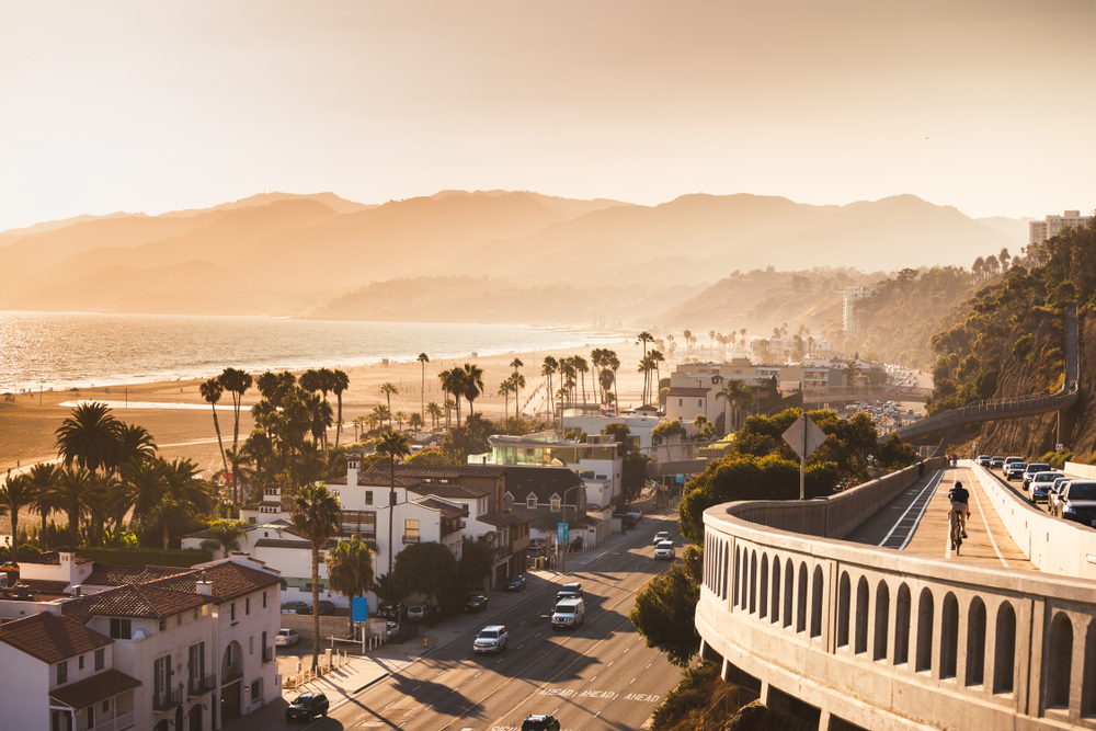 Santa Monica, a beautiful view of the beach, ocean,  mountains, buildings, and highway.