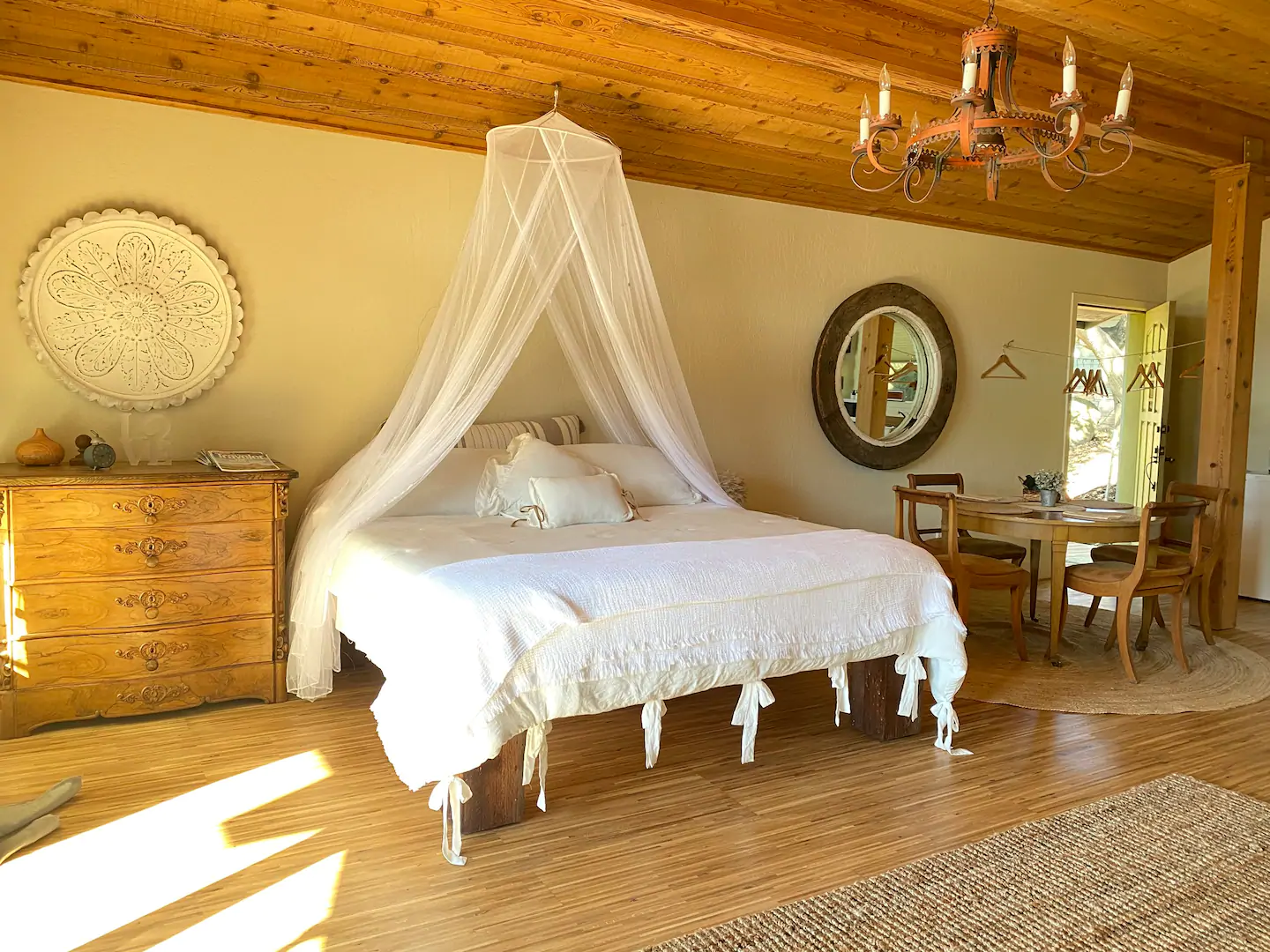 Dreamy, neutral and white-tones bedroom and table area of this Sonoma Airbnb in California!  Shows lovely bed with canopy drape.