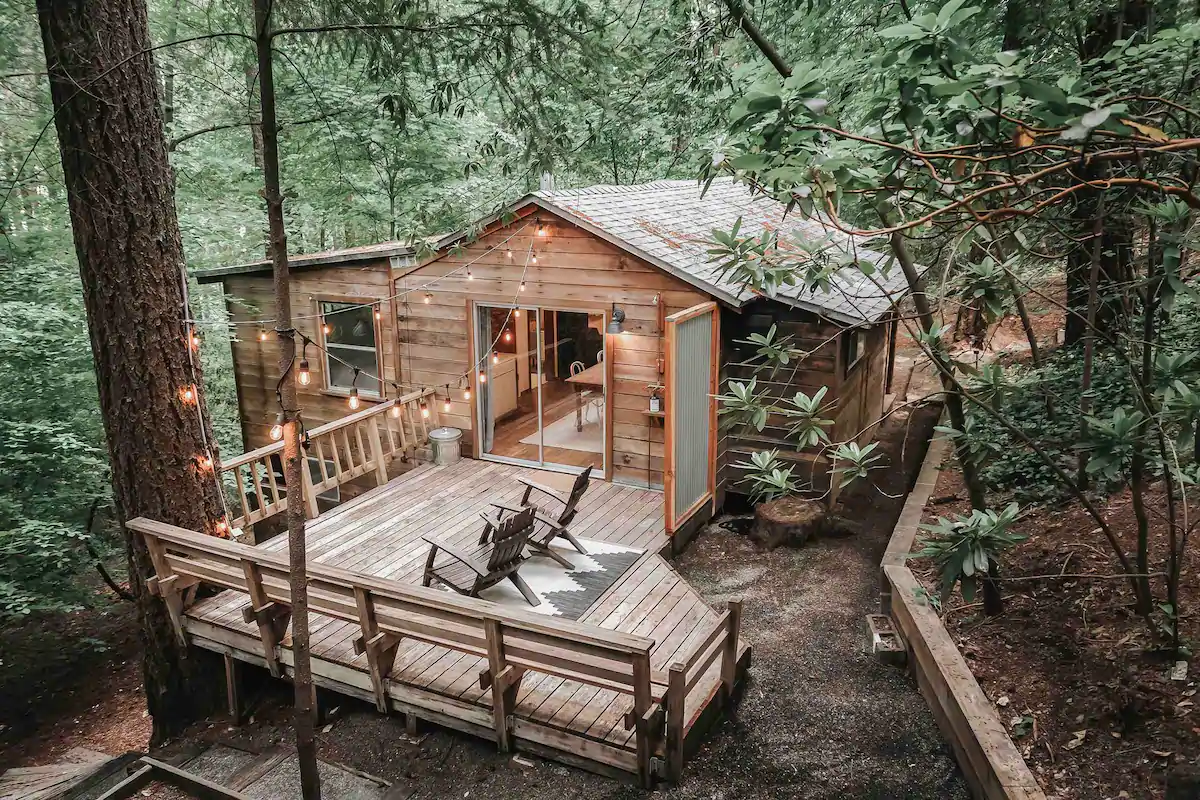 Pretty, minimalistic California Airbnb cabin in the woods of Cobb, with a deck and bistro lights strung overhead. 