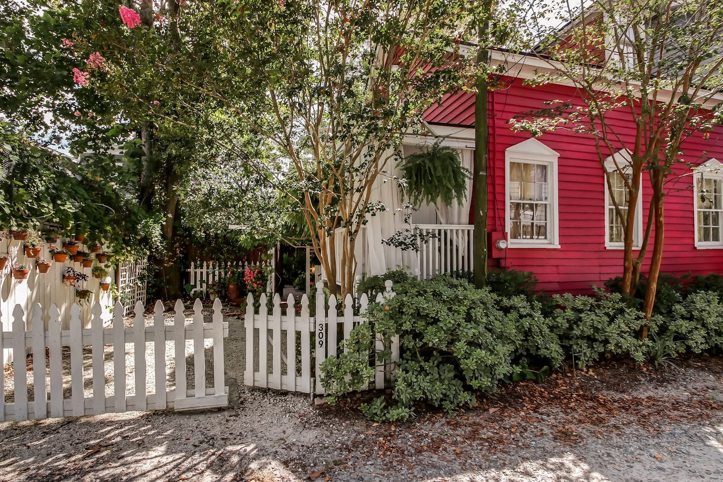 exterior view of the adorable hot pink Miss Rose Cottage that is surrounded by a beautiful garden. This is one of the best cabins in Savannah