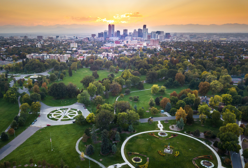 Aerial view of Denver at sunset with a park in the foreground and the city skyline in the background.