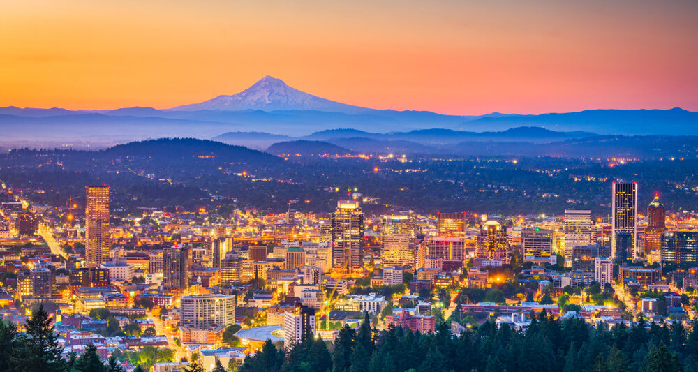 Portland city skyline at sunset with Mt. Hood visible in the distance.