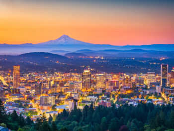 Portland city skyline at sunset with Mt. Hood visible in the distance.