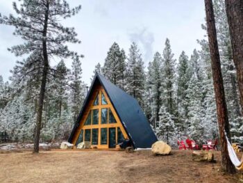 a frame cabin surrounded by tall pines dusted in snow one of the most cozy cabins in Idaho