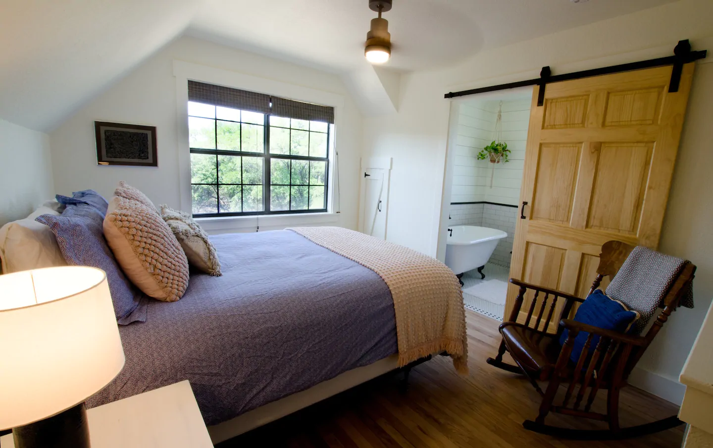 A beautiful master bedroom and bathroom, with natural lighting, a gorgeous sliding barn door, and a claw foot tub.  Lovely cabin getaway in Texas!