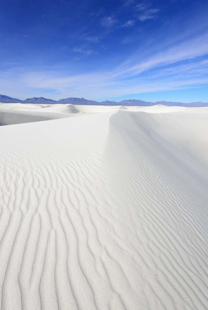 Untouched pure white sand stretches out for miles with mountain ranges on the horizon at the Alkali Flats Trail