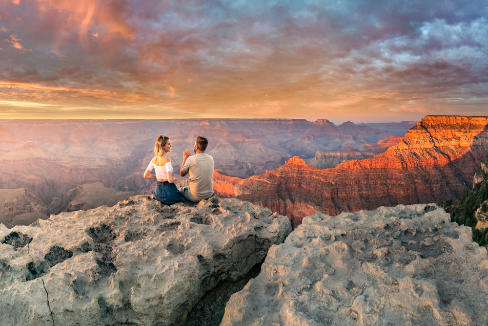 A couple sitting at the Grand Canyon during sunset