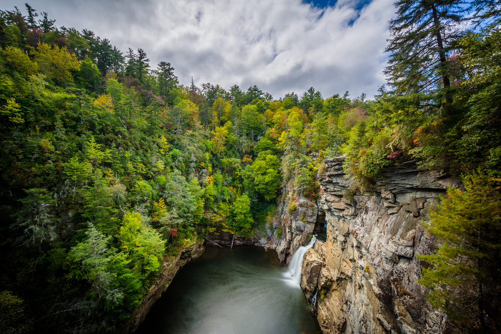 The view looking down at one of the waterfalls at Linville Falls that drops into a pool of water surrounded by lush forest