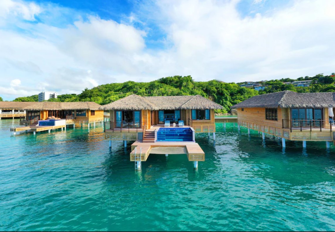 A view of several overwater bungalows in a line each with a private deck that has a plunge pool and a ladder that gives you direct access to the ocean