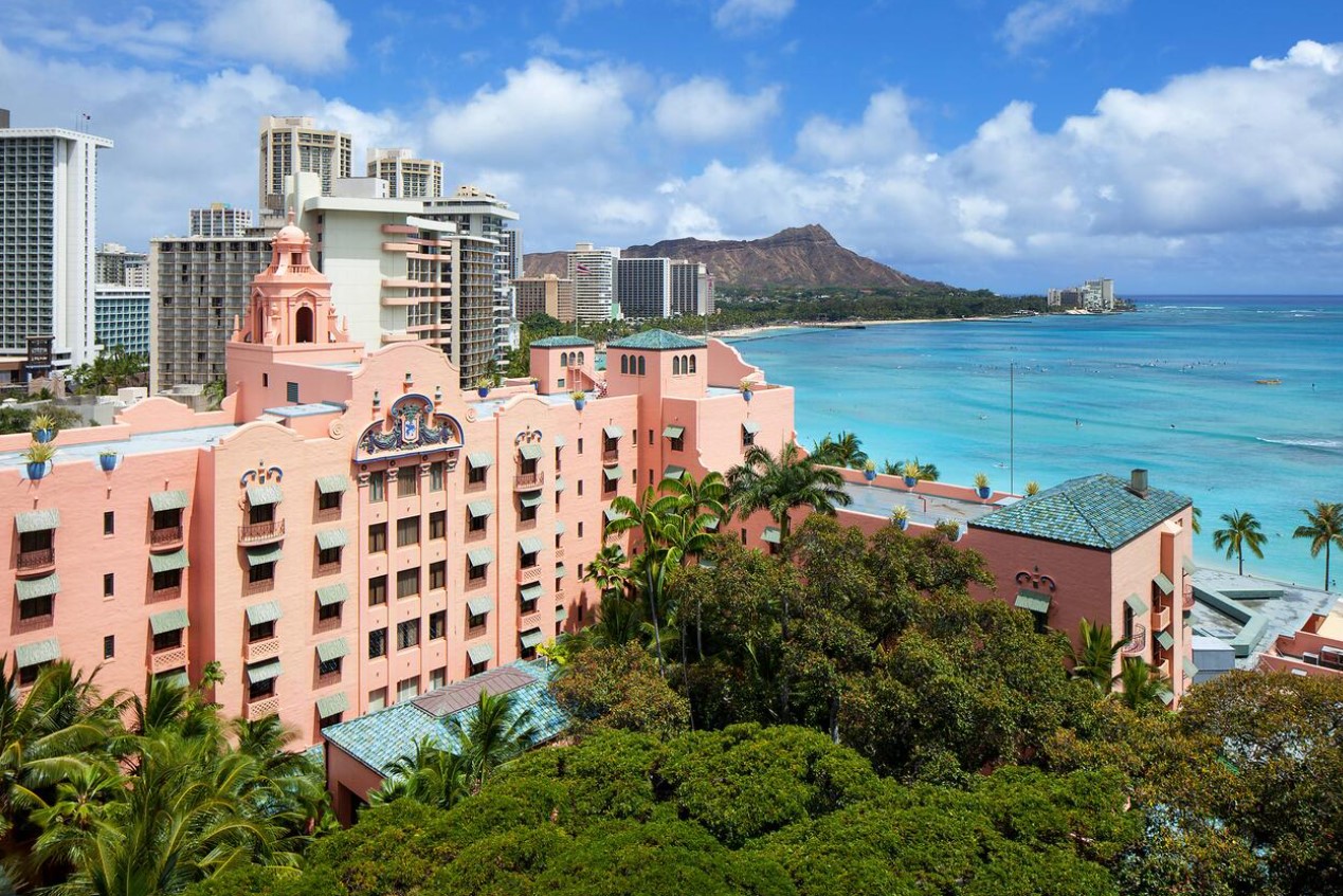 The pink Royal Hawai'ian Resort on the shores of Waikiki Beach with the Diamond Head Crater behind it one of the most romantic honeymoon destinations in the usa