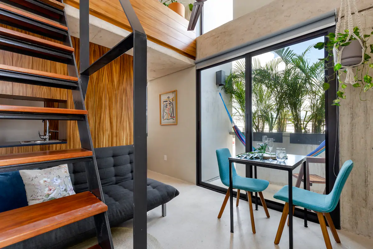 The elegant dark wood kitchen, private terrace with hammock, and table for 2 at this loft in Cancun. 