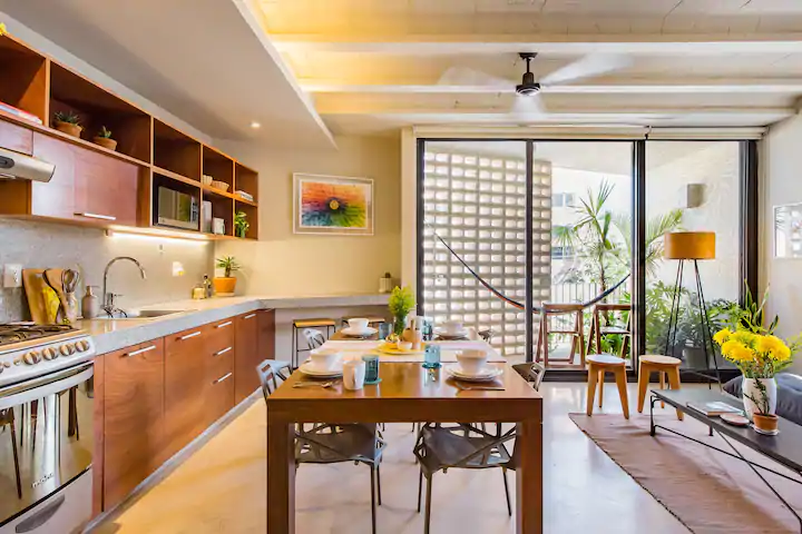 A designer apartment is a great place to stay in Cancun! It has a spacious kitchen, table for 4, and a terrace covered in plants.