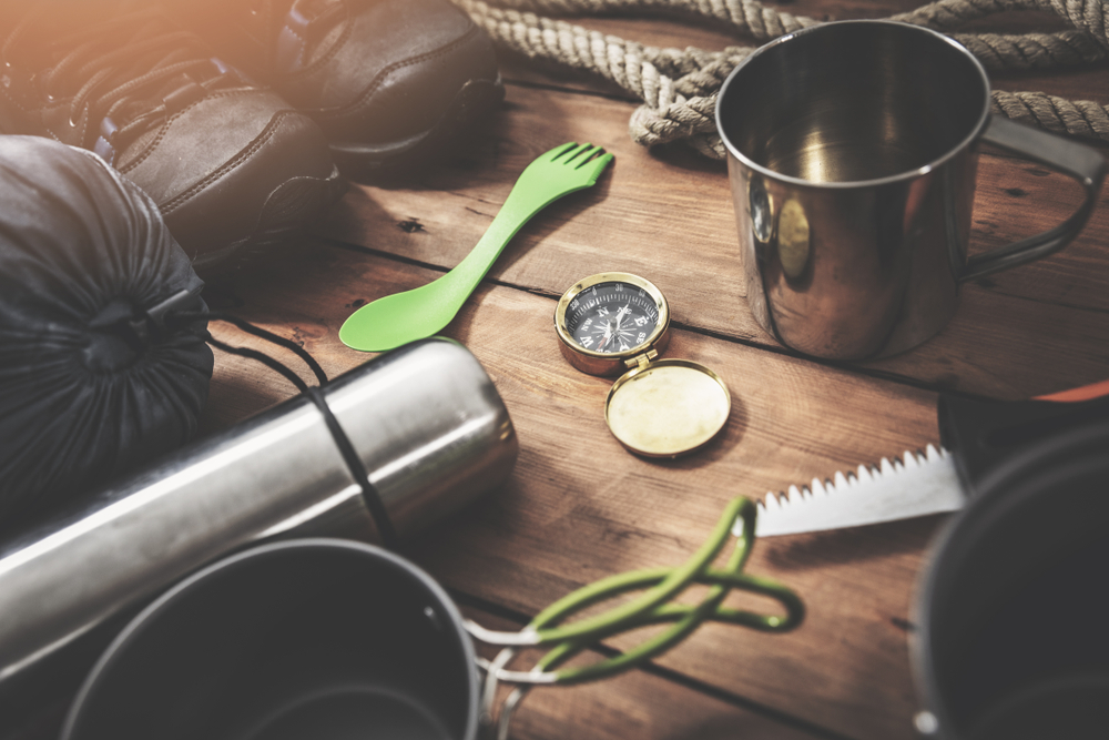 photo of a spork, hiking boots, and a compass, all important car camping essentials