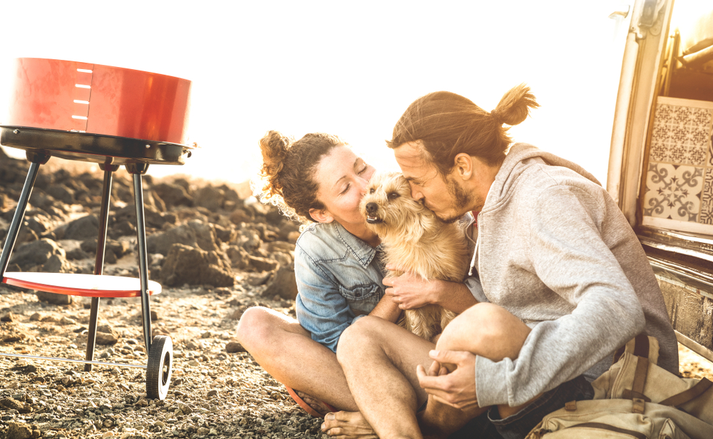 photo of a dog and a couple wearing jackets, one of the important car camping essentials
