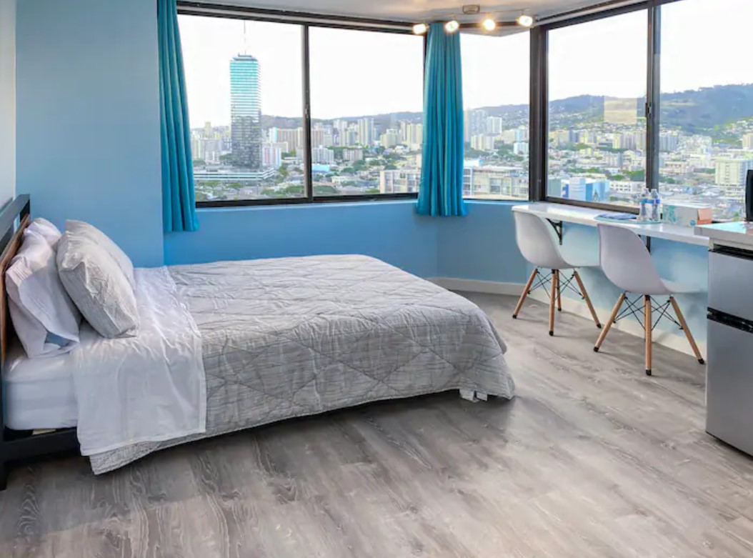 The interior of a high rise studio apartment painted blue with 180 degree views of the Honolulu skyline best airbnbs in Hawaii