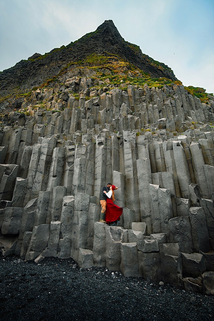 photo of couple on rocks with mountain in background