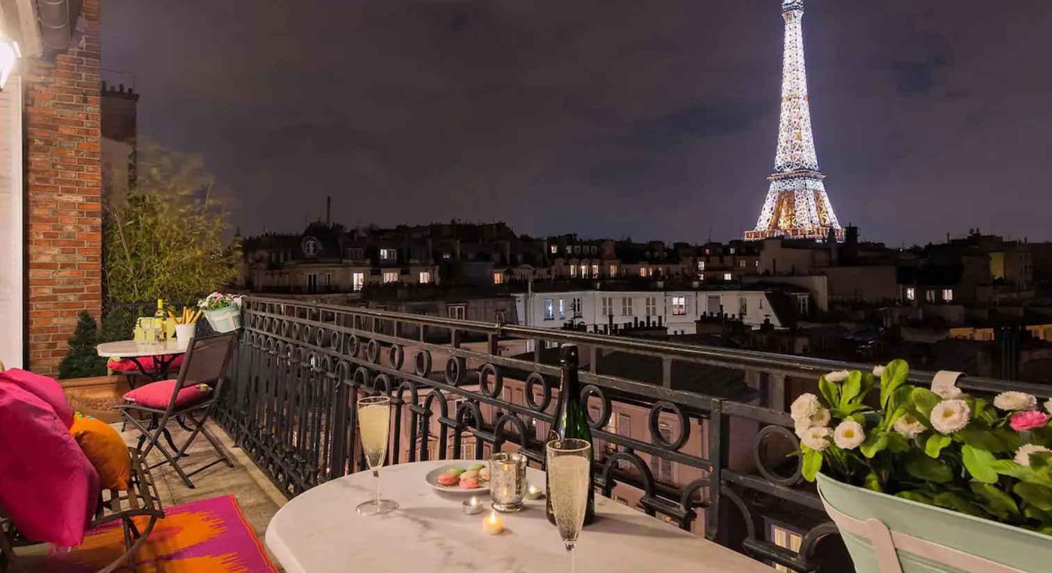 The view of the Eiffel Tower lit up at night from a large private terrace in an apartment in Paris