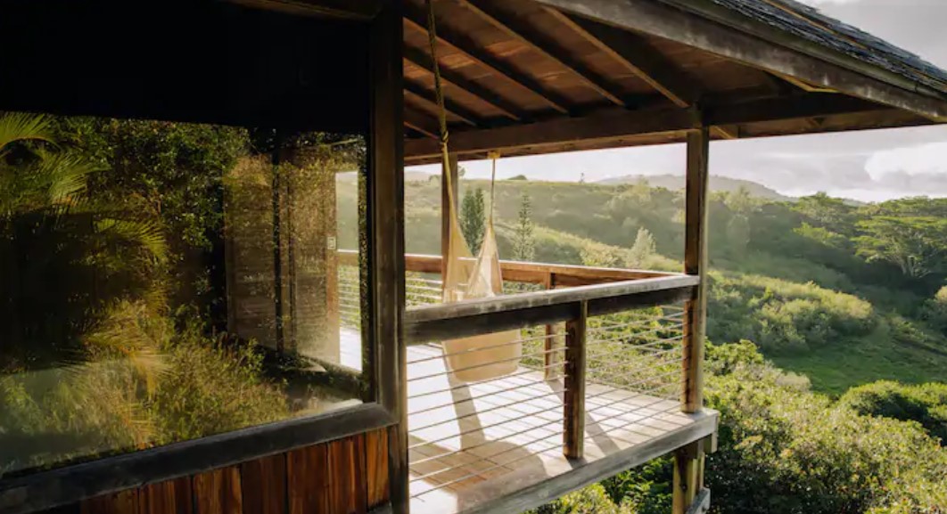 A treehouse in the hills of Hawaii with views of the mountains and a hammock on a lanai.