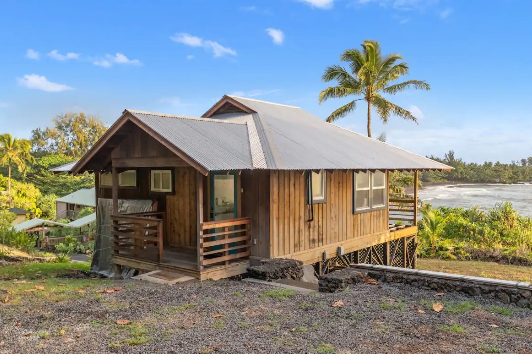 The exterior view of a wooden cottage on the edge of a beautiful tropical bay one of the best airbnbs in Hawaii