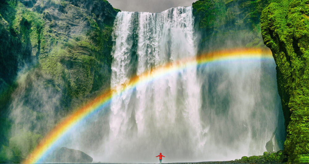 An article about rainbow quotes featuring a girl standing in front of a waterfall.