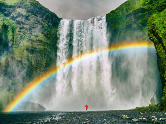 An article about rainbow quotes featuring a girl standing in front of a waterfall.