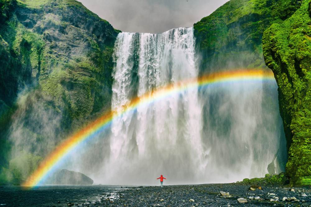 An article about rainbow quotes featuring a girl standing in front of a waterfall.