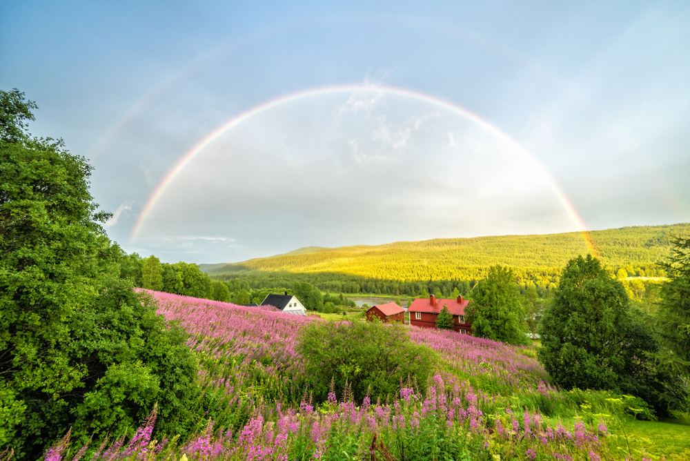 A rainbow over a field with a house in the background in a article about rainbow quotes