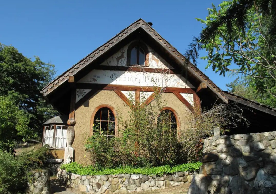 The exterior of the Gnome House with a stone wall, Scandinavian art painted on the house, and a small garden area best Airbnbs in Washington