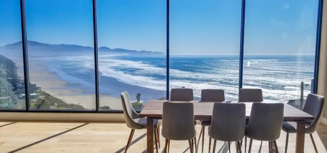 a dining room with floor to ceiling windows that look out to the Pacific Ocean