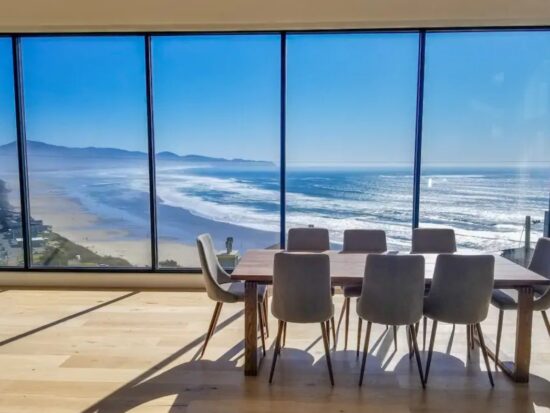 a dining room with floor to ceiling windows that look out to the Pacific Ocean
