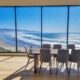 a dining room with floor to ceiling windows that look out to the Pacific Ocean