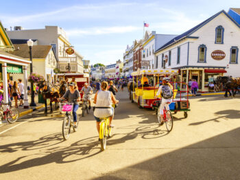 people biking on the streets of Mackinac Island one of the best small town beaches in the usa