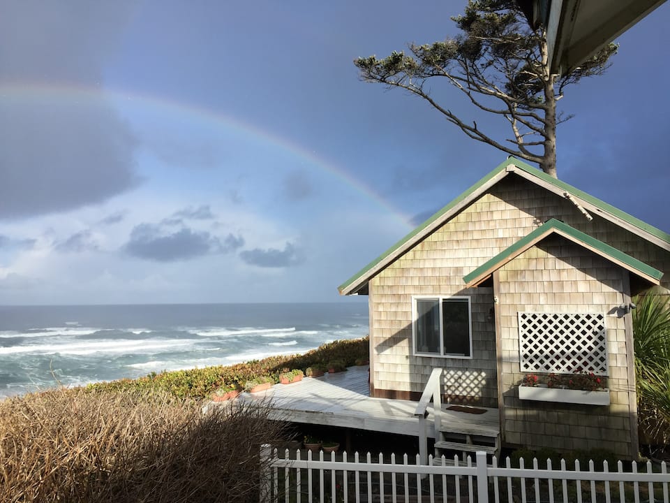 A cute cottage directly on the beach with stunning ocean views and a rainbow in the sky.