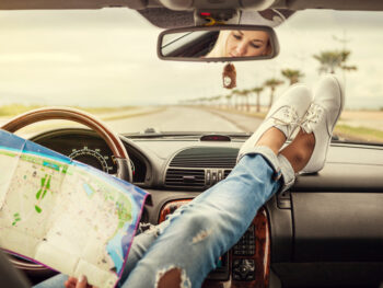 Girl with feet on dashboard of a car in an article about road trip questions