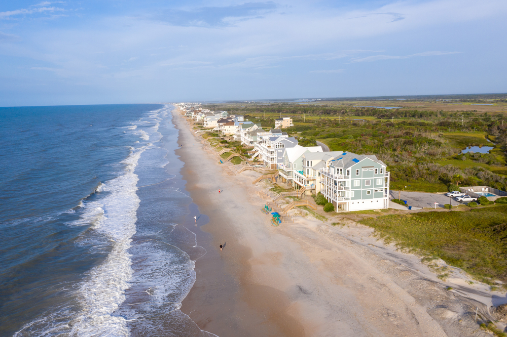 An aerial image looking down the shore line where there are large beach homes on Topsail Beach North Carolina