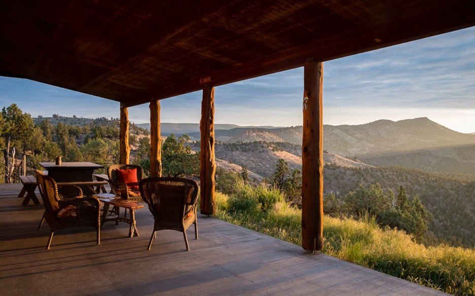 The front porch of a large cabin in Central Oregon that has views of Oregon's highest desert at sunset